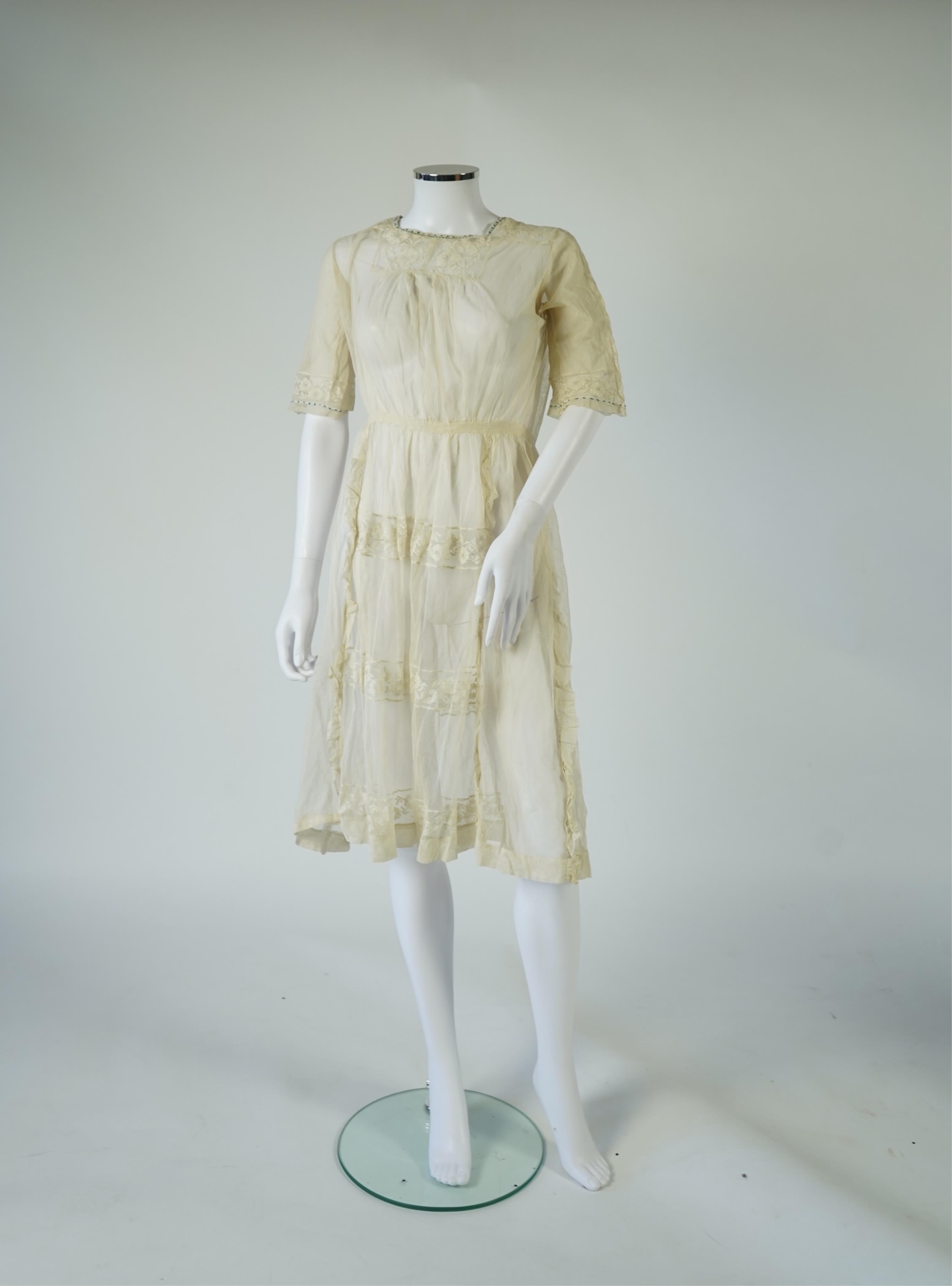 An early 20’s cream net ladies summer dress and net petticoat, designed with a lace inset front skirt, yolk and sleeves.103cm long. Condition - both need re-laundering and some seams tidying.
